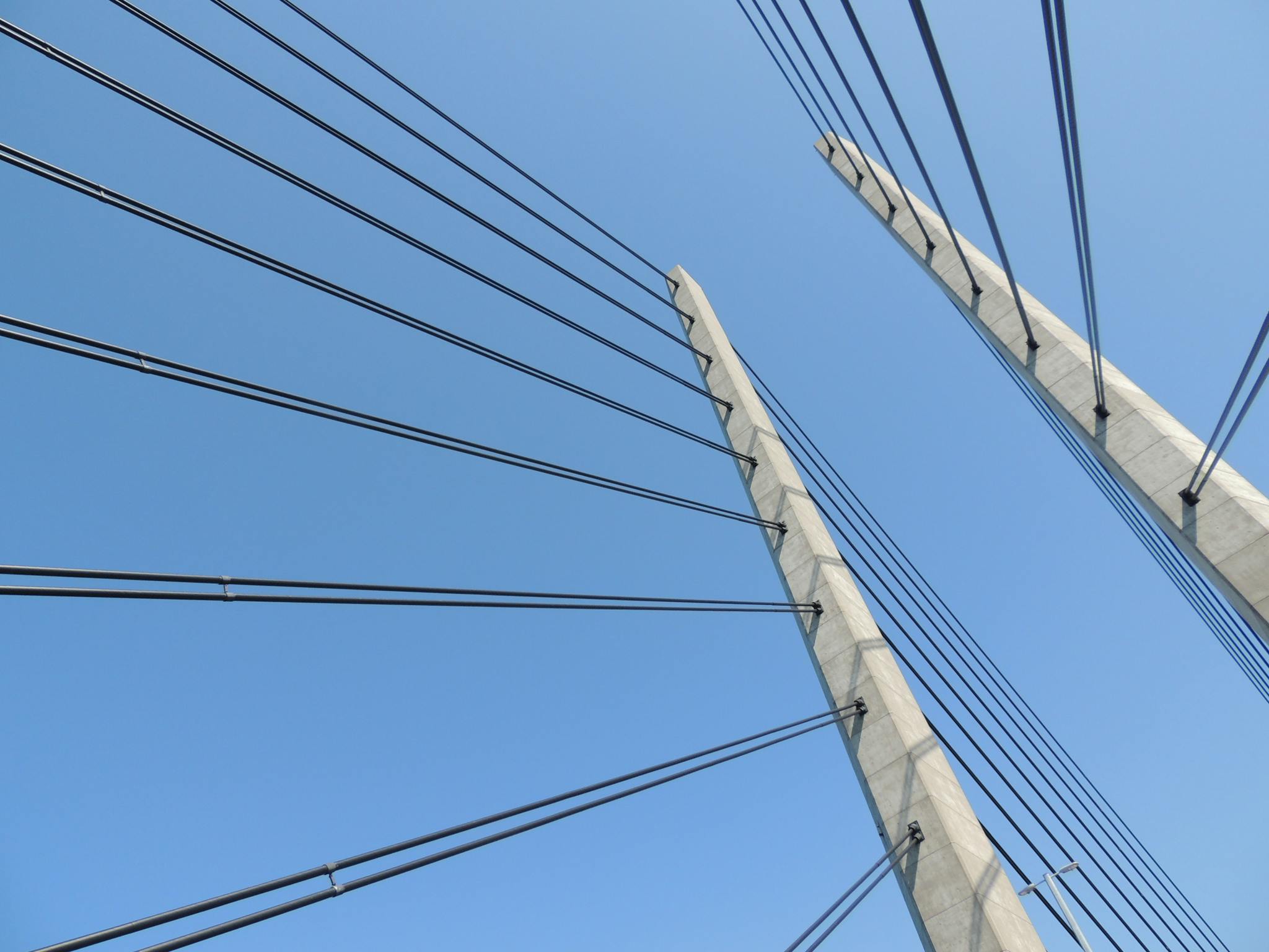 A modern suspension bridge with steel cables set against a clear blue sky, showcasing architectural elegance.