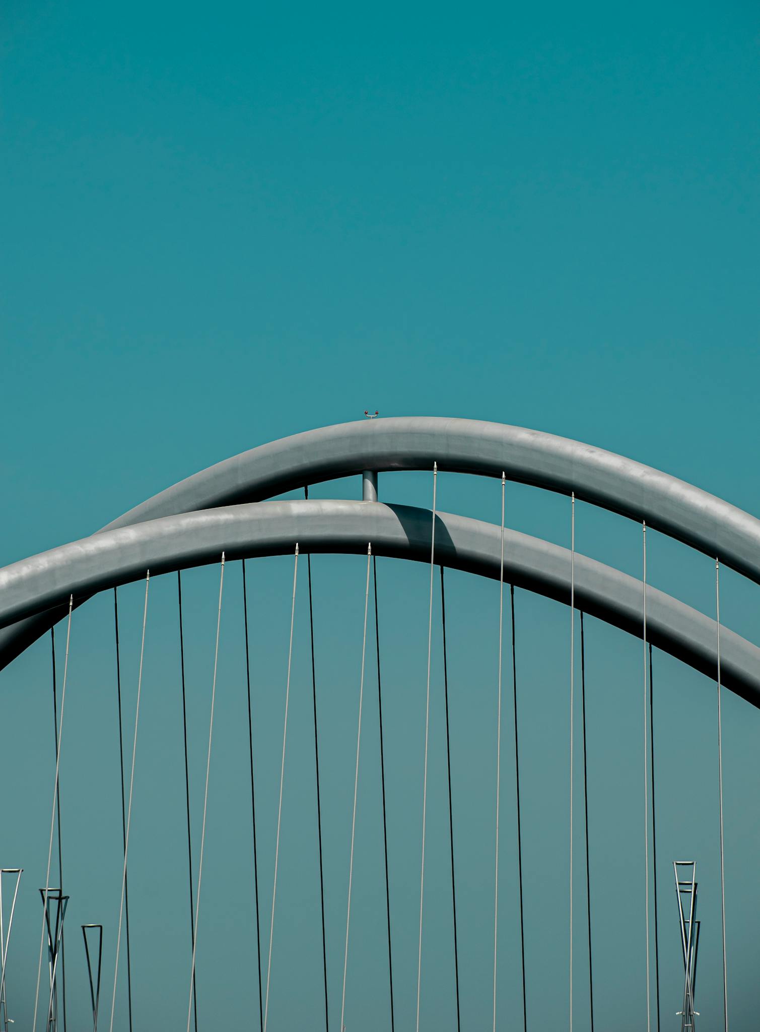 Close-up of a modern steel arch bridge structure against a clear blue sky, showcasing urban design.