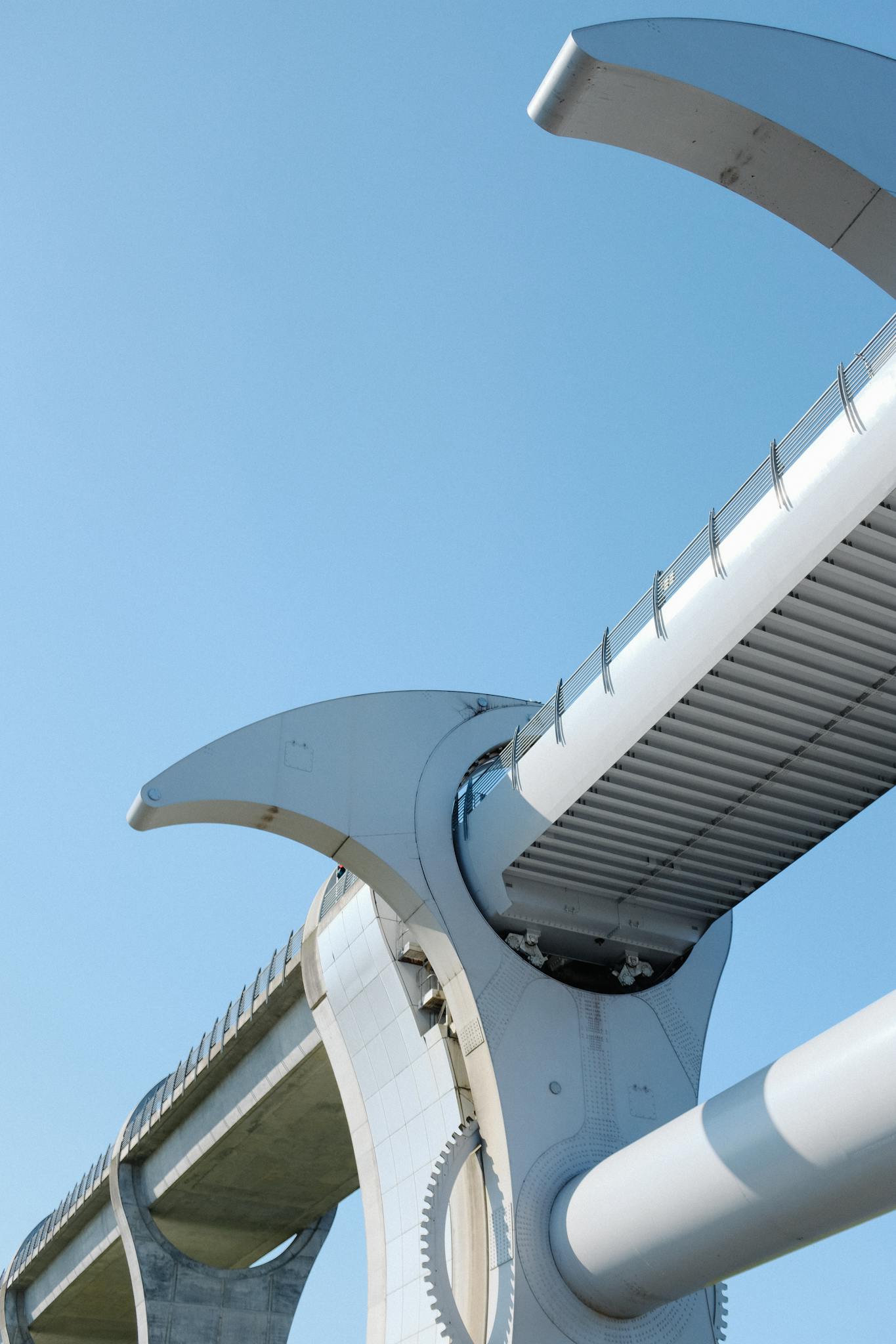 Low-angle view of a futuristic bridge showcasing modern architecture against a clear blue sky.
